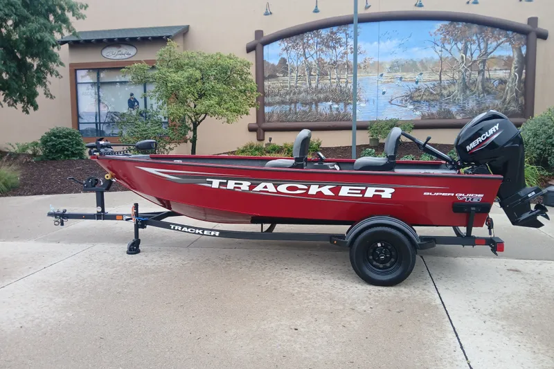 The Image of 2027 Tracker Super Guide V-16 SC boat on trailer, red exterior, parked outdoors. - 0