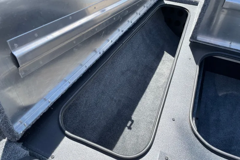 Slide: The Image of Storage compartment of 2027 Tracker Pro Team 175 boat, featuring carpeted interior and metal frame. - 18