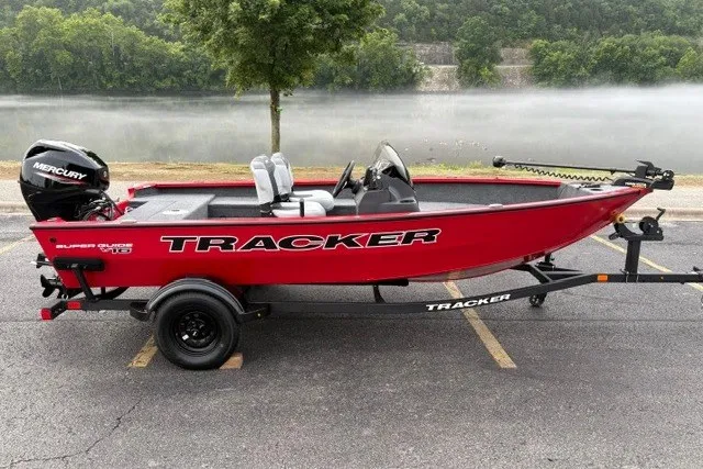 The Image of Red 2027 Tracker Super Guide V-16 SC boat on trailer by a lake. - 0