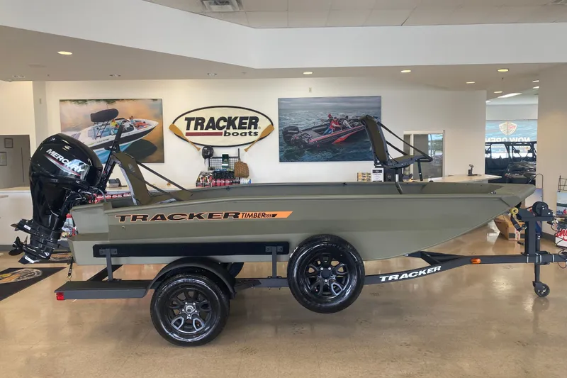 The Image of 2027 Tracker Grizzly 1553 Timber boat displayed in showroom with Mercury outboard motor. - 0