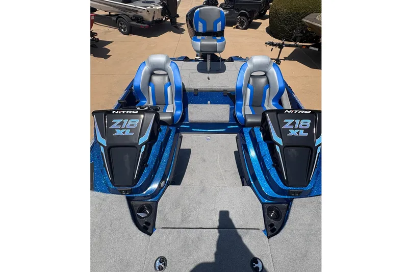 Slide: The Image of 2027 Nitro Z18 XL boat with blue and gray seating, parked on a sunny day. - 7
