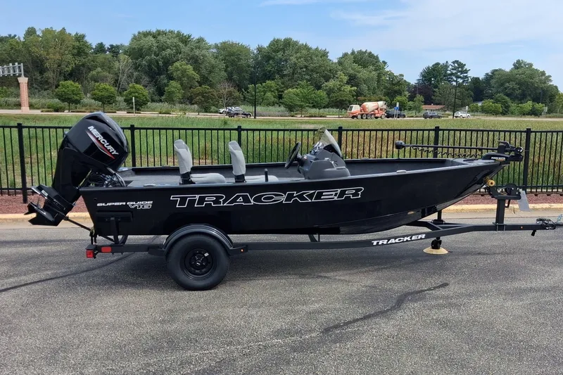The Image of 2027 Tracker Super Guide V-16 SC fishing boat on trailer, parked outdoors. - 0
