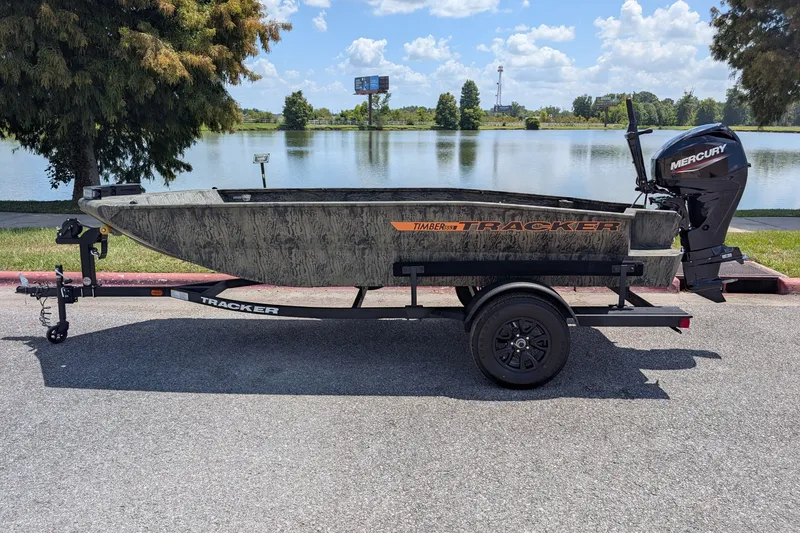 The Image of 2027 Tracker Grizzly 1553 Timber boat on trailer by a lake, sunny day. - 0