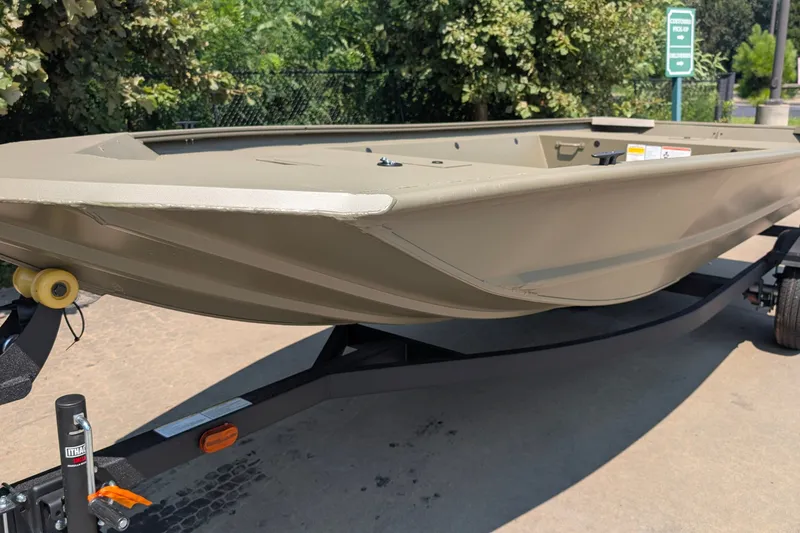 The Image of 2027 Tracker Grizzly 1648 Utility boat on trailer, outdoors with greenery background. - 0