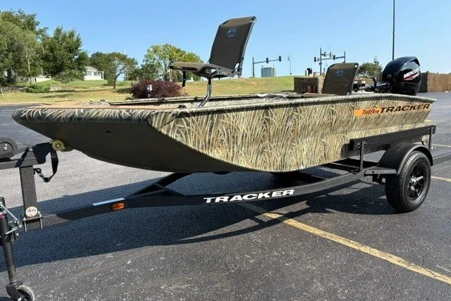 The Image of 2027 Tracker Grizzly 1553 Timber boat on trailer, camo design, parked outdoors. - 0