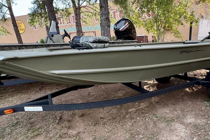 The Image of 2027 Tracker Grizzly 1654 T Sportsman boat on trailer, outdoors near trees. - 0