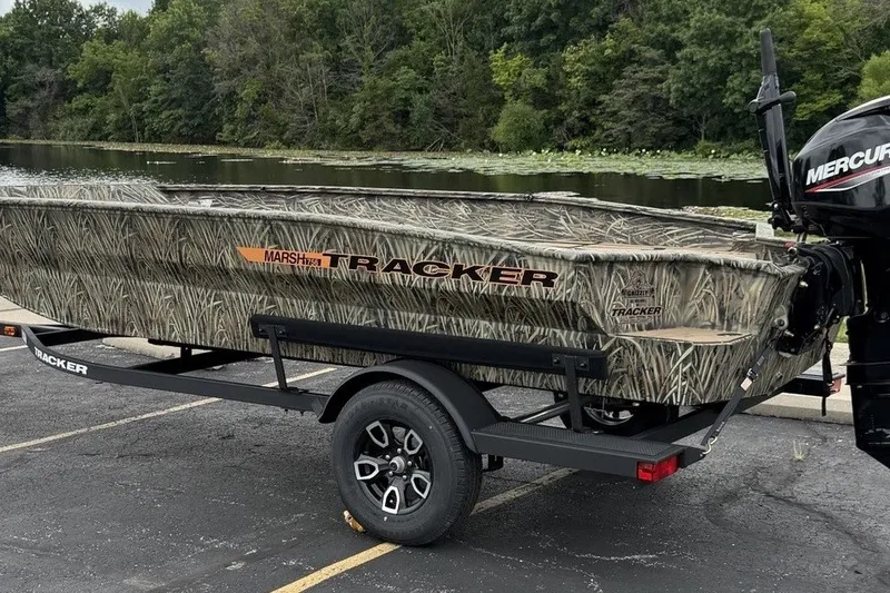 The Image of 2027 Tracker Grizzly 1756 T Marsh boat on trailer by a lake. - 0
