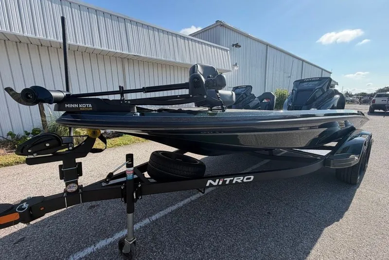 Slide: The Image of 2027 Nitro Z18 XL boat with Minn Kota motor on trailer, parked outdoors. - 1