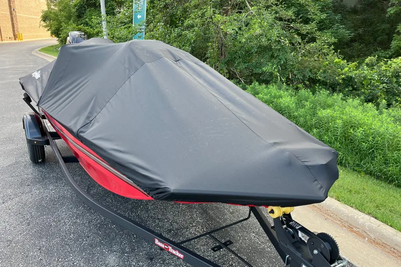 Slide: The Image of 2027 Tracker Bass Tracker Classic XL boat covered, parked on a trailer near greenery. - 23