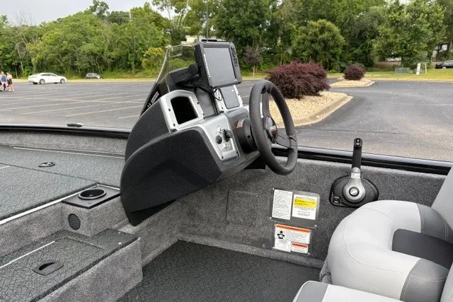 Slide: The Image of 2027 Tracker Pro Team 175 boat interior with steering wheel and control panel in parking lot. - 17