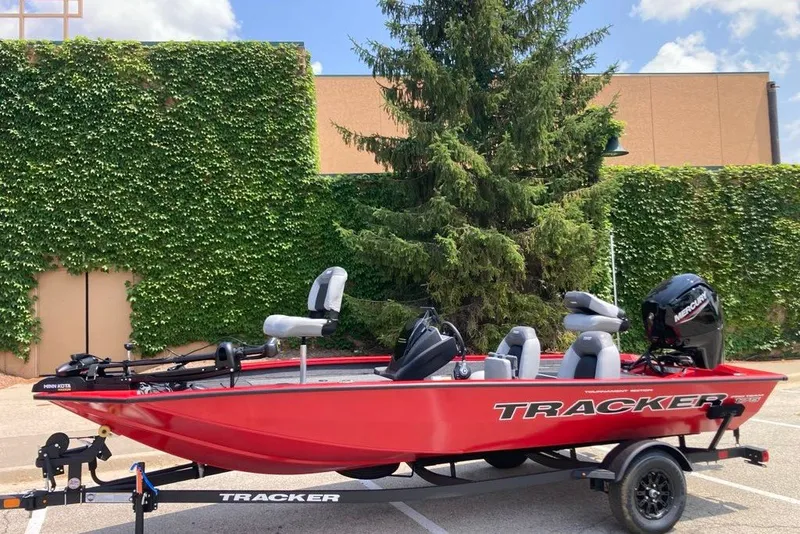 The Image of 2027 Tracker Pro Team 175 boat on trailer, parked outdoors with greenery background. - 0