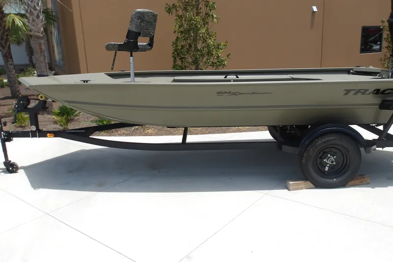 The Image of 2027 Tracker Grizzly 1654 T Sportsman boat on trailer, parked outdoors. - 0