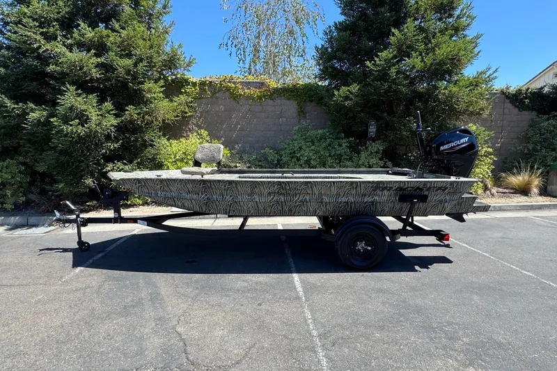 The Image of 2027 Tracker Grizzly 1654 T Sportsman boat on trailer, parked outdoors. - 0