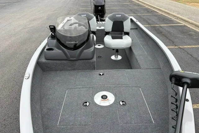 Slide: The Image of 2027 Tracker Super Guide V-16 SC fishing boat with dual seats and console in parking lot. - 16