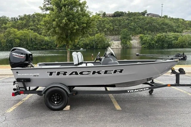 The Image of 2027 Tracker Super Guide V-16 SC boat on trailer by a scenic river. - 0
