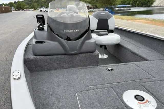 Slide: The Image of 2027 Tracker Super Guide V-16 SC fishing boat with seating and console, docked by a lake. - 17
