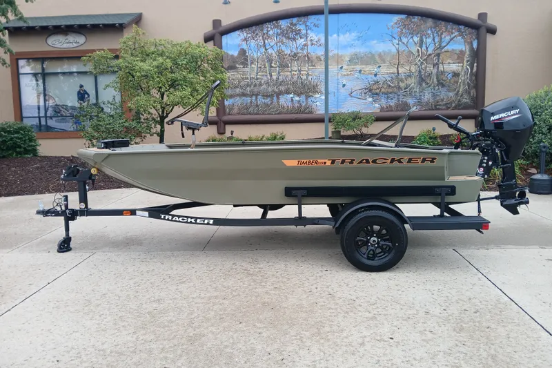 The Image of 2027 Tracker Grizzly 1553 Timber boat on trailer, parked outdoors with scenic mural backdrop. - 0