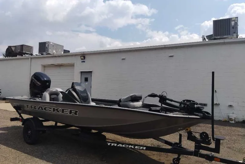 The Image of 2027 Tracker Pro Team 175 boat on trailer, parked outdoors near a white building. - 0
