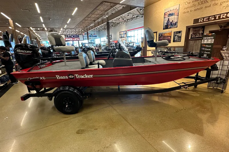 The Image of 2027 Tracker Bass Tracker Classic XL boat displayed indoors, featuring red exterior and Mercury engine. - 1