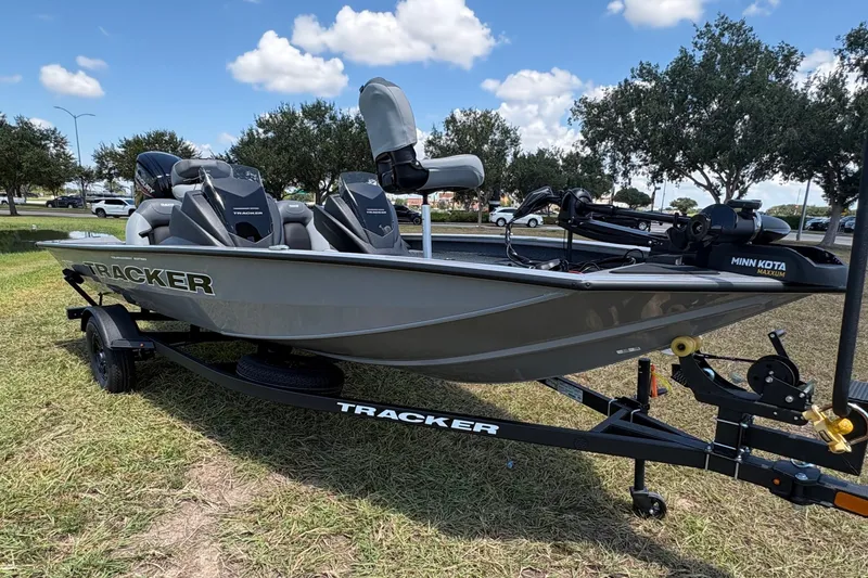 The Image of 2027 Tracker Pro Team 175 boat on trailer, parked on grass under blue sky. - 0