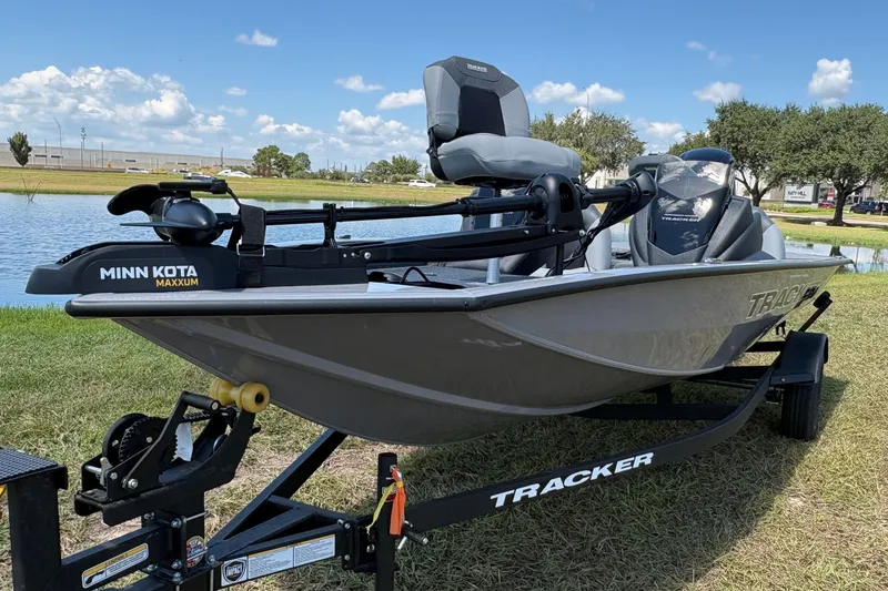 The Image of 2027 Tracker Pro Team 175 boat on trailer by a lake under blue sky. - 0