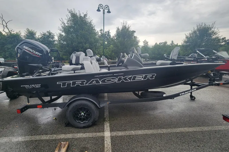 The Image of 2027 Tracker Pro Team 175 boat on trailer, parked outdoors on a cloudy day. - 0