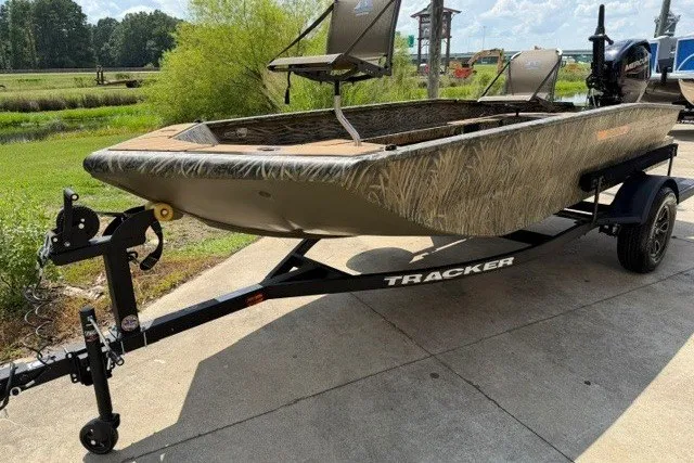 The Image of 2027 Tracker Grizzly 1553 Timber boat on trailer, parked outdoors, showcasing camo design. - 0