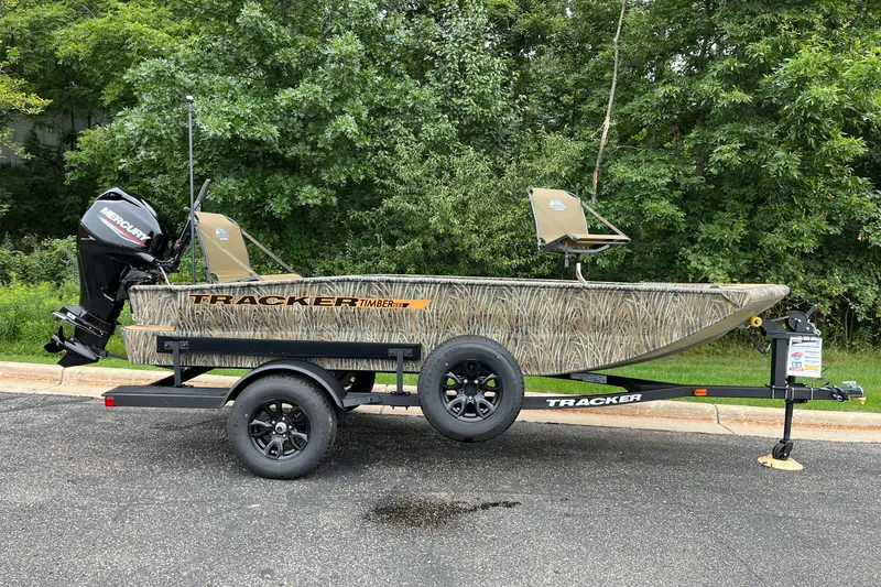The Image of 2027 Tracker Grizzly 1553 Timber boat on trailer, parked on asphalt with green foliage background. - 0