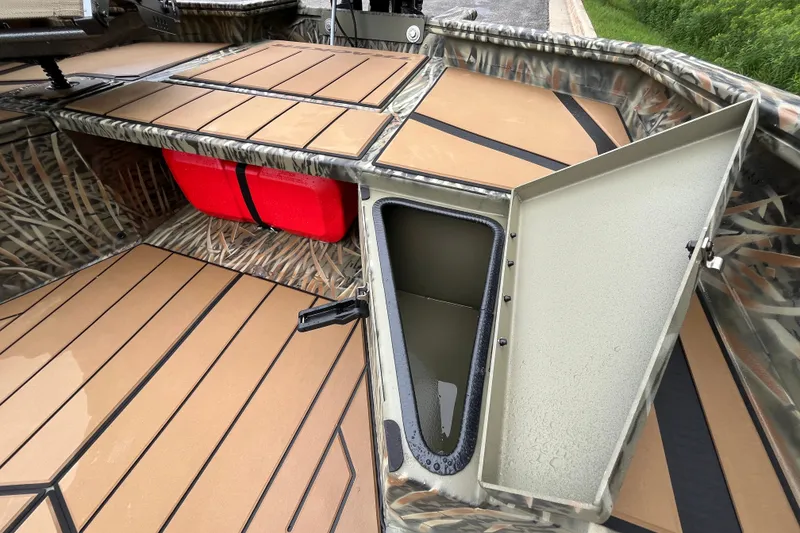Slide: The Image of 2027 Tracker Grizzly 1553 Timber boat interior with open storage compartment and camouflage design. - 27