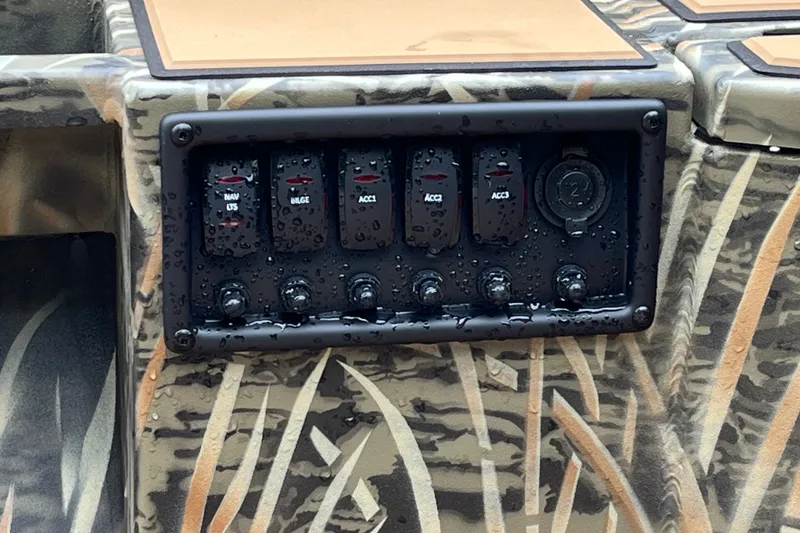 Slide: The Image of Control panel of 2027 Tracker Grizzly 1553 Timber boat with switches and camo design. - 29