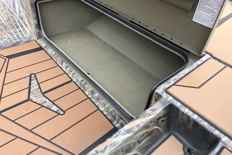 Slide: The Image of Open storage compartment in 2027 Tracker Grizzly 1553 Timber boat with camo and wood-patterned flooring. - 18
