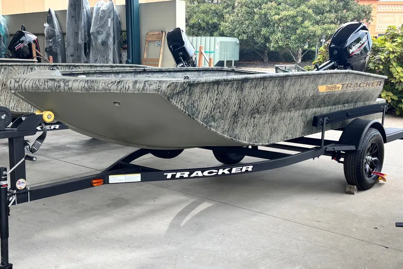 The Image of 2027 Tracker Grizzly 1553 Timber boat on trailer, camo design, parked outdoors. - 0