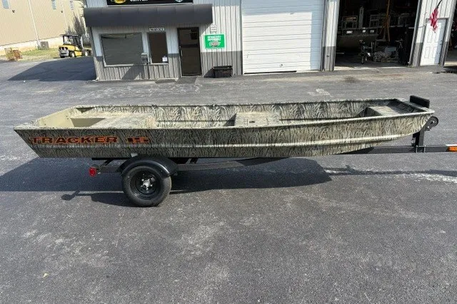 The Image of 2027 Tracker Grizzly 15 Jon boat on trailer, parked outside a garage. - 0