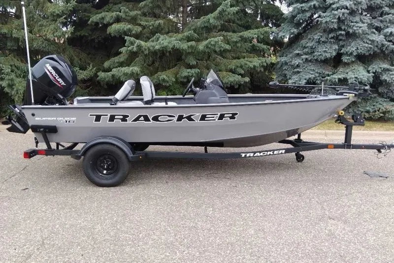 The Image of 2027 Tracker Super Guide V-16 SC fishing boat on trailer, parked outdoors. - 0