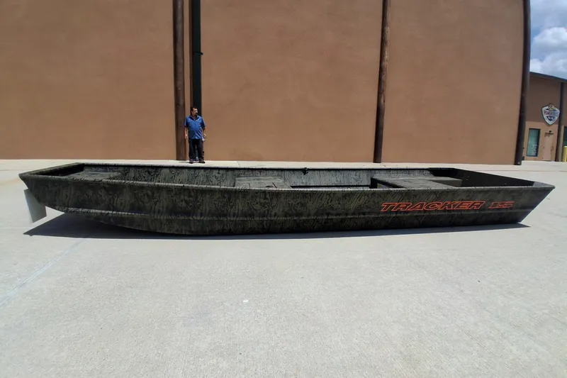 The Image of 2027 Tracker Grizzly 15 Jon boat on concrete, person standing nearby. - 0