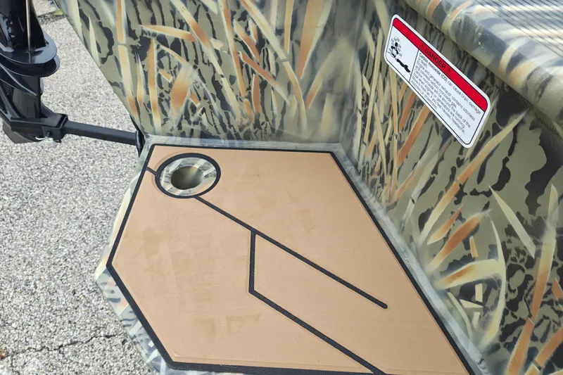 Slide: The Image of Camouflage-patterned Tracker Grizzly 1553 Timber boat detail, featuring a warning label, 2027 model. - 21
