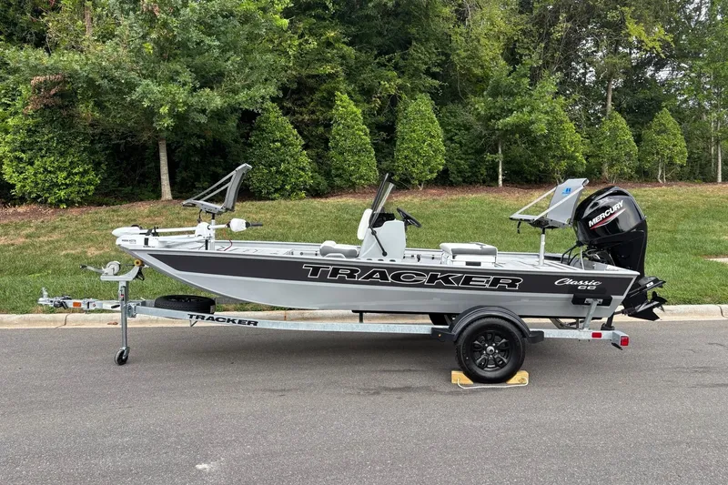 The Image of 2027 Tracker Bass Tracker Classic CC boat on trailer, parked on road with greenery background. - 0
