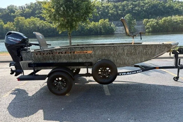 The Image of 2027 Tracker Grizzly 1553 Timber boat on trailer, parked by a scenic river. - 0