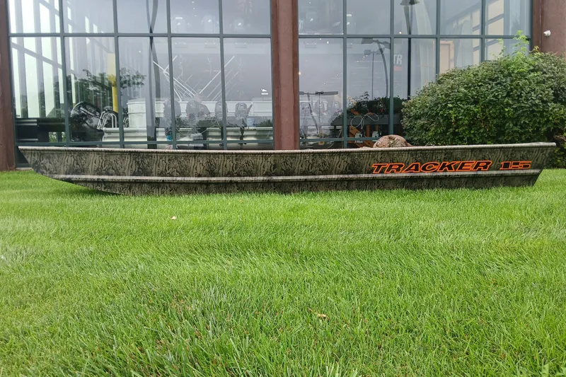 The Image of 2027 Tracker Grizzly 15 Jon boat displayed on grass outside a building. - 0