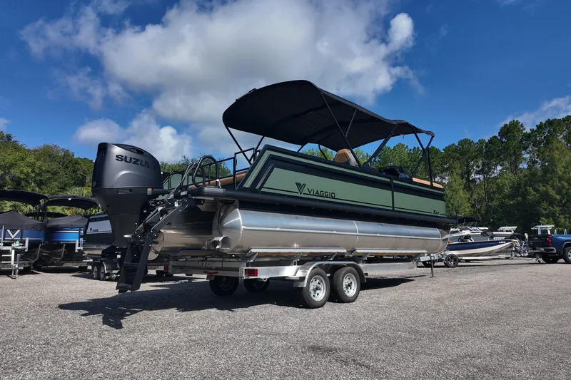 Slide: The Image of 2027 Viaggio X22S pontoon boat on trailer, featuring Suzuki outboard motor, under a clear blue sky. - 2