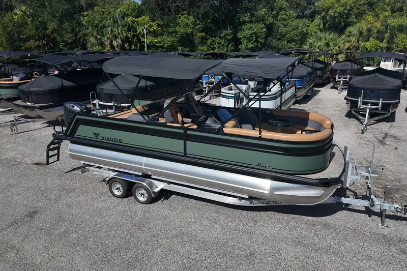 The Image of 2027 Viaggio X22S pontoon boat on trailer, parked outdoors with other boats. - 0