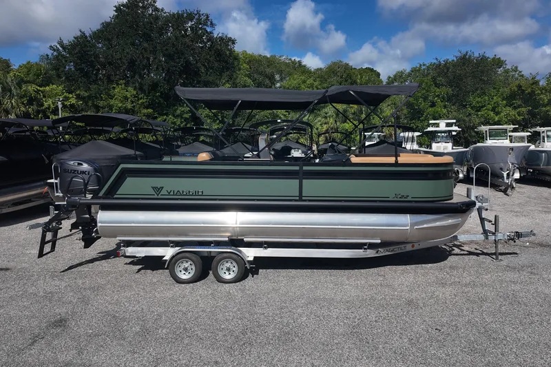 Slide: The Image of 2027 Viaggio X22S pontoon boat on trailer, parked outdoors under a blue sky. - 1