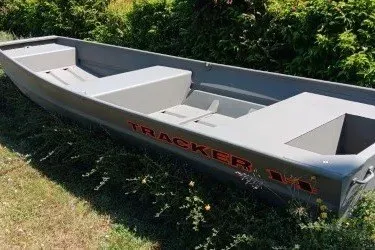 The Image of 2027 Tracker Grizzly 14 Jon boat in grassy area, showcasing sleek design and durable build. - 0