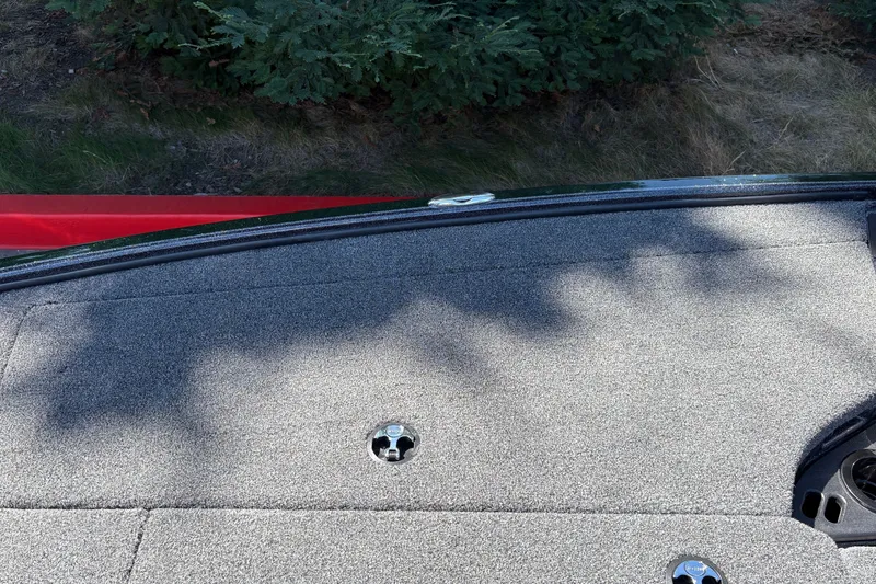 Slide: The Image of Carpeted deck of a 2027 Nitro Z18 XL boat with greenery in the background. - 40