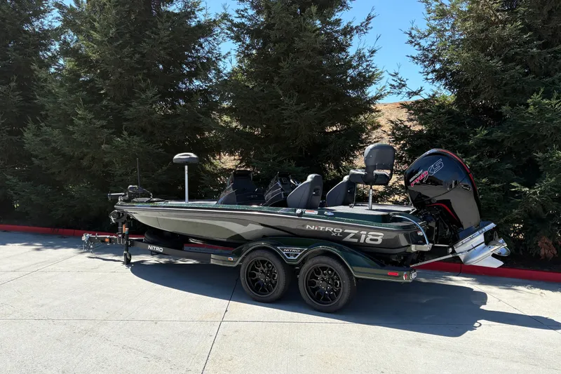 Slide: The Image of 2027 Nitro Z18 XL boat parked outdoors, surrounded by trees. - 5