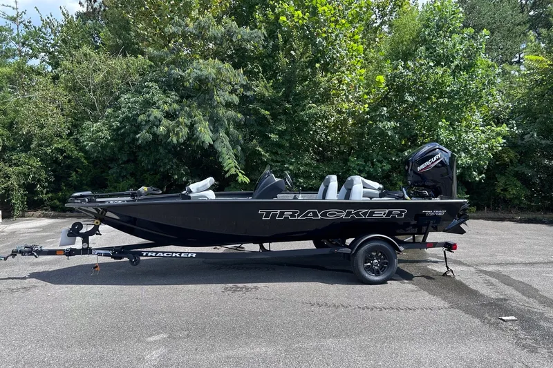 The Image of 2027 Tracker Pro Team 175 boat on trailer, parked outdoors with lush greenery background. - 0