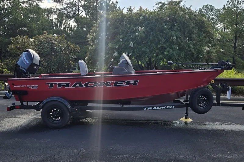 The Image of Red 2027 Tracker Super Guide V-16 SC boat on trailer, parked outdoors. - 0
