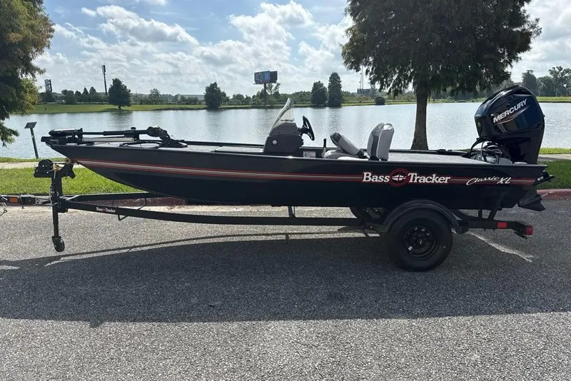 The Image of 2027 Tracker Bass Tracker Classic XL boat by a lake under a cloudy sky. - 0