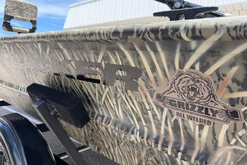Slide: The Image of 2027 Tracker Grizzly 1654 T Sportsman boat with camo design and Grizzly logo. - 13