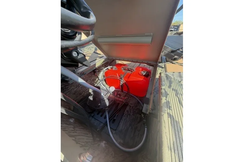 Slide: The Image of Open compartment of 2027 Tracker Grizzly 1553 Timber showing red fuel tanks and hoses. - 26